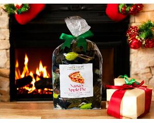 Nana's Apple Pie Potpourri by Irish Twins Potpourri sits on a wooden table in front of a fireplace with Christmas stockings and ornaments.